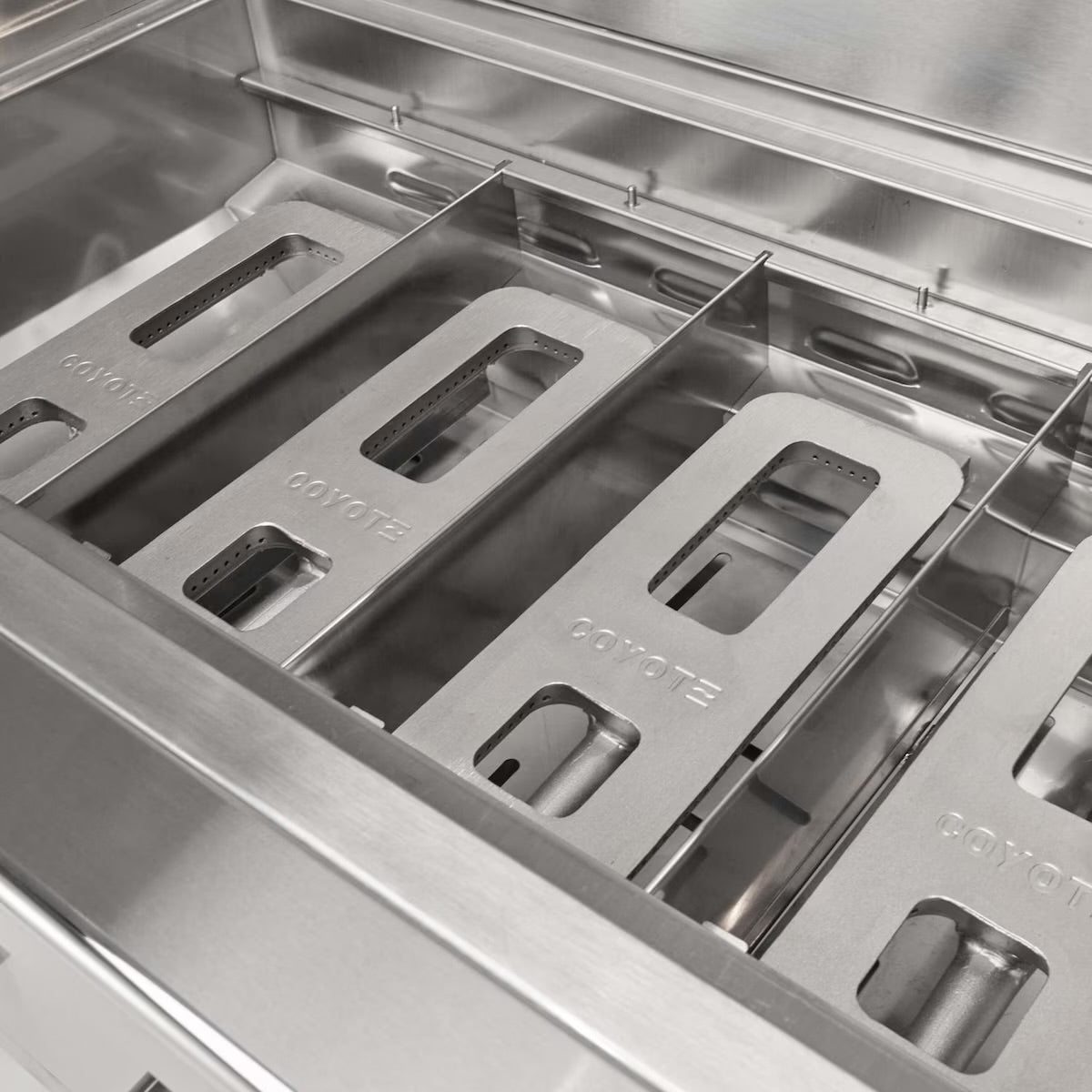 Stainless steel burners with 'Coyote' branding on a grill.