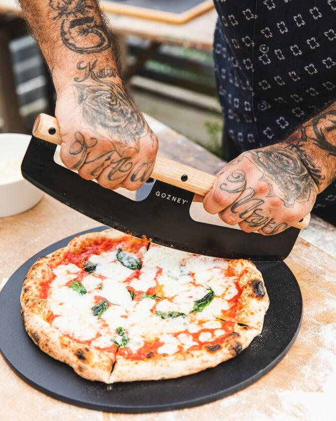 Gozney 14" black pizza server with pizza being cut 