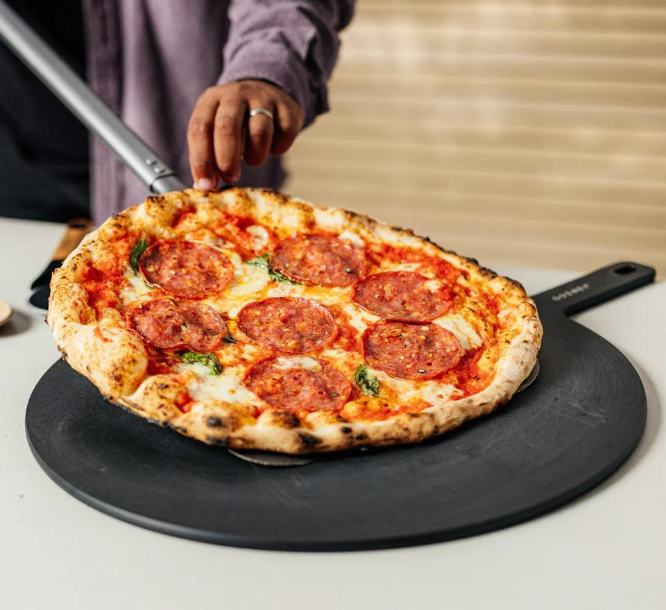 Gozney Black 18" round pizza server with a pizza on it 