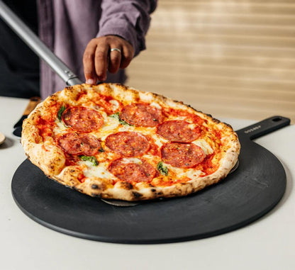 Gozney Black 18" round pizza server with a pizza on it 