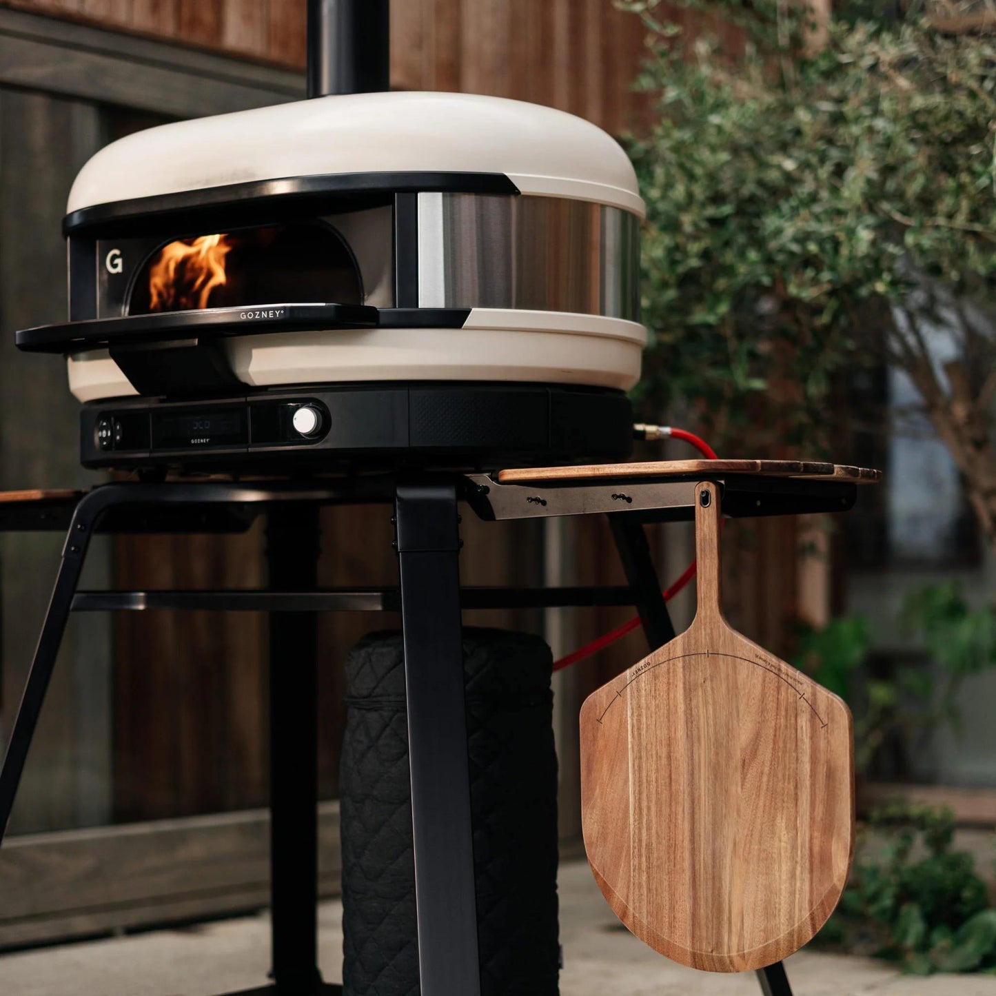 Gozney Acacia Wood pizza peel hanging from a Gozney Pizza Oven