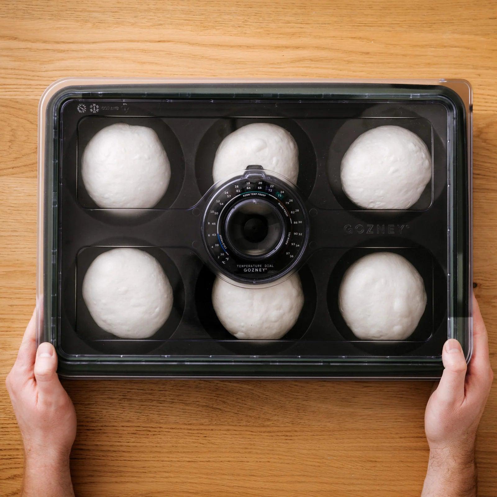 Gozney Dough Tray with dough balls and lid on a wooden surface