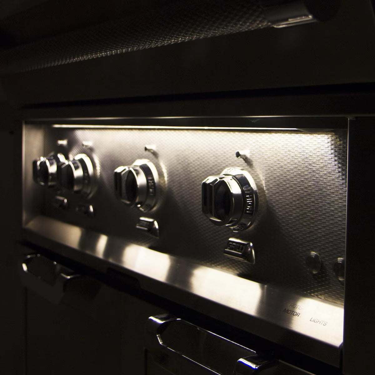 Hestan 30" Built In Gas Grill at night time with knob lights on