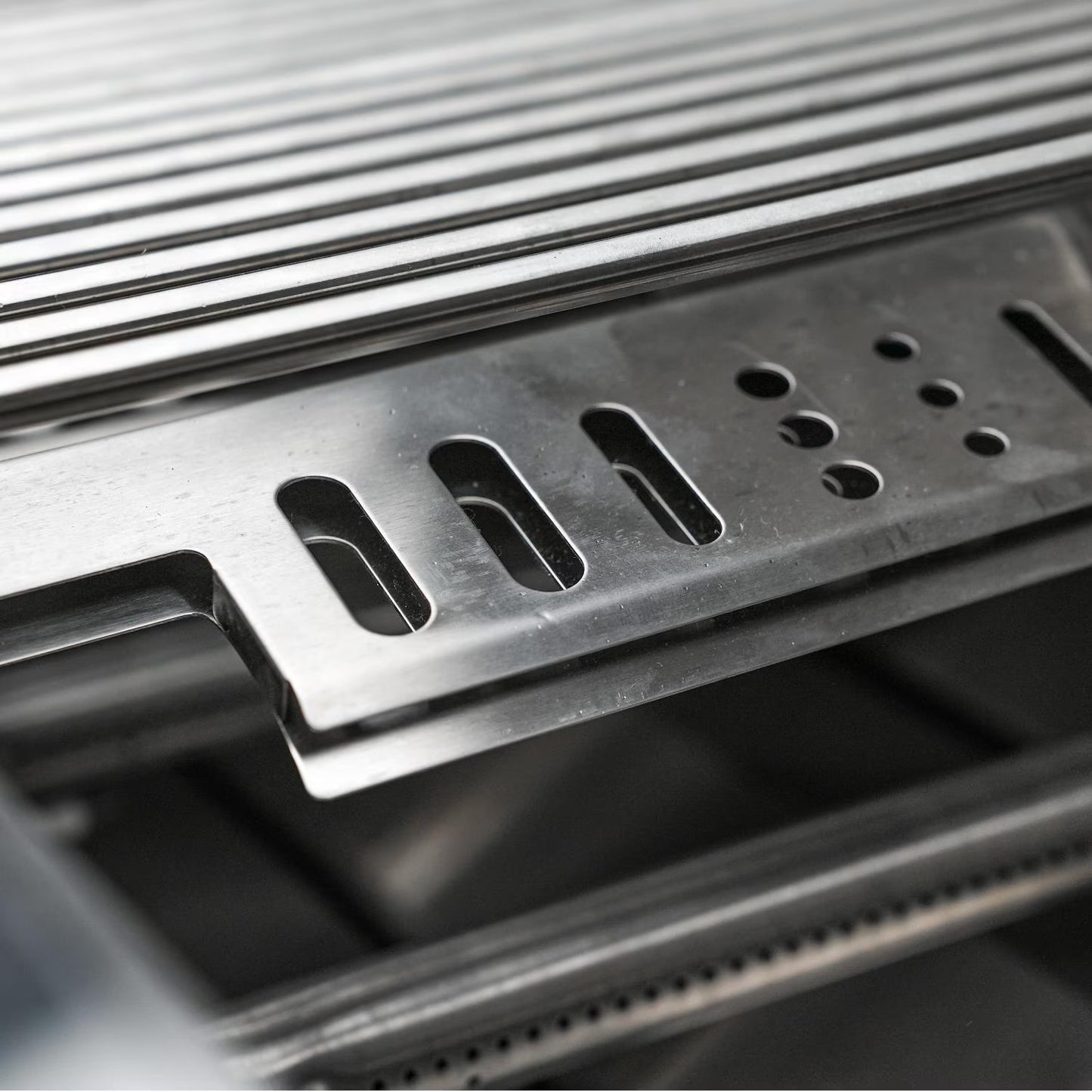 Close-up of a Mont Alpi metallic grill grate on a dark background