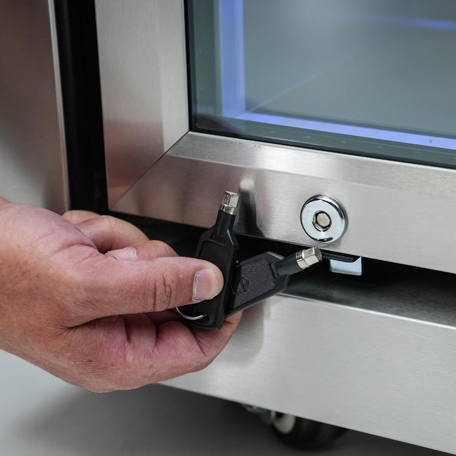 Person inserting a key into a lock on a Mont Alpi refrigerator 
