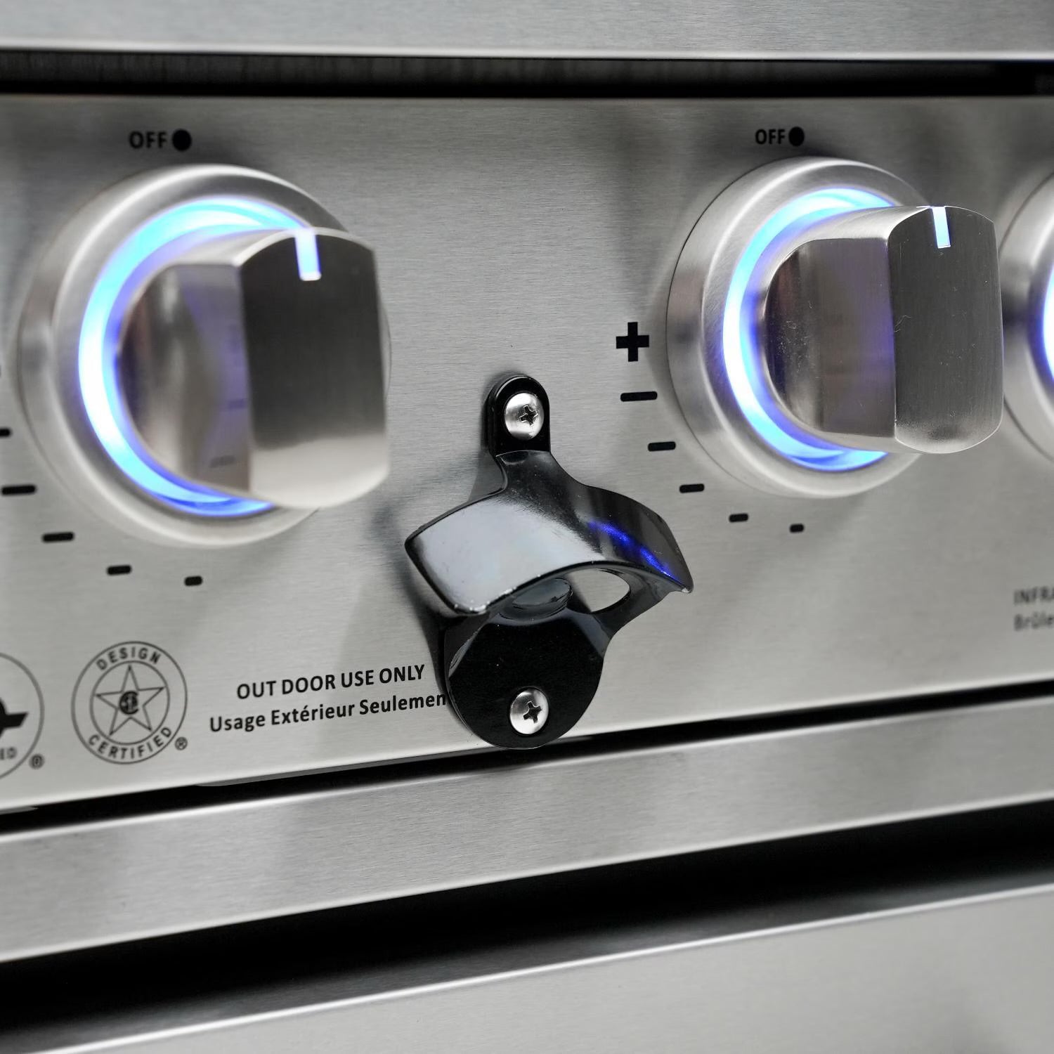 Mont Alpi Stainless steel outdoor grill control panel with two knobs and a lock, featuring blue ignition lights.