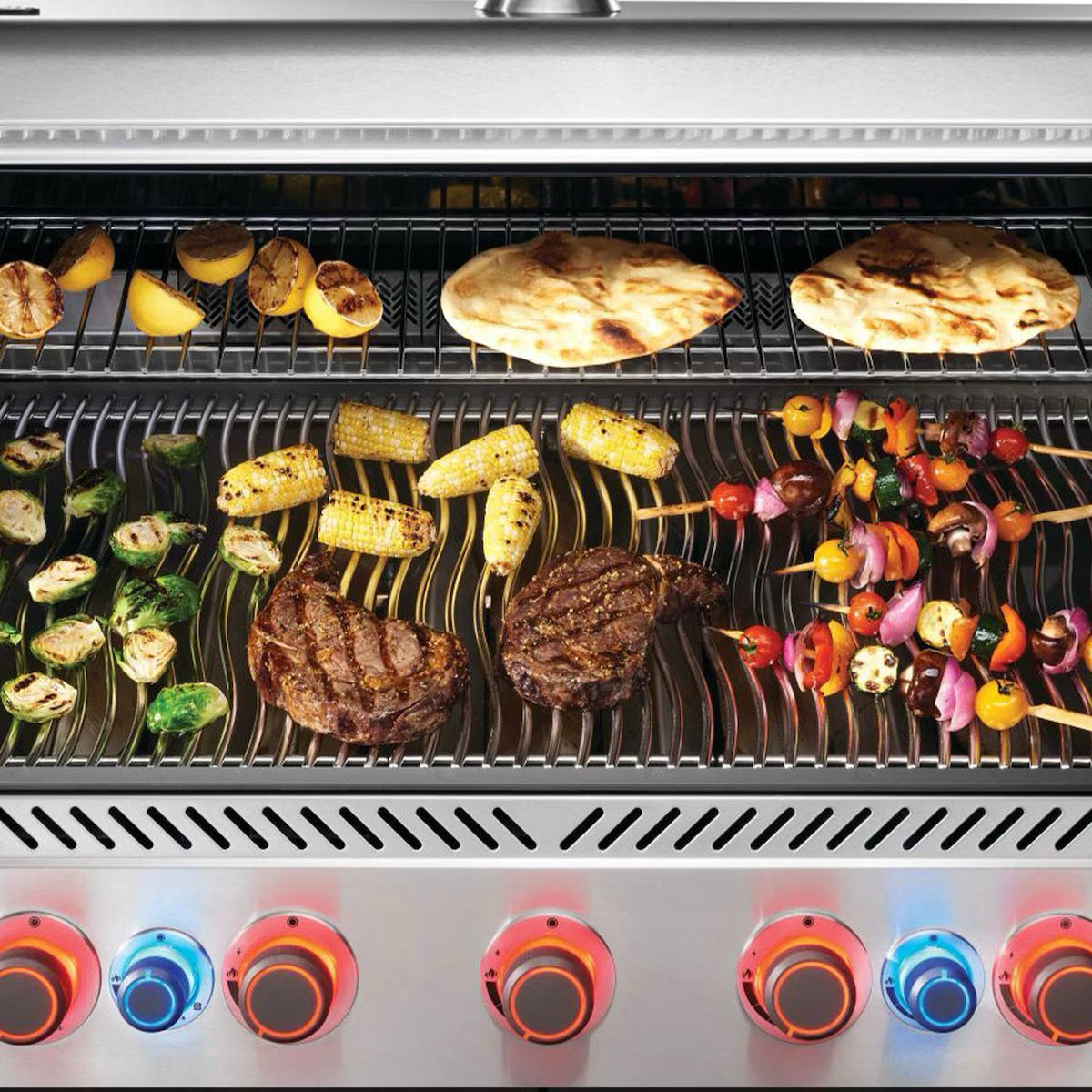 Napoleon Prestige 665 5-Burner Grill with Rotisserie & Side Burner with food grilling on it with illuminated knobs