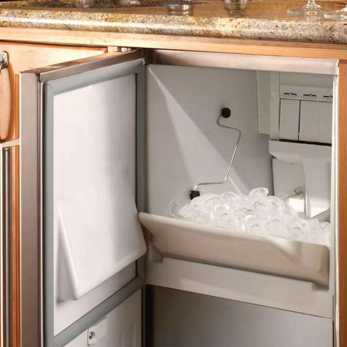 Ice maker in a kitchen cabinet with ice cubes visible