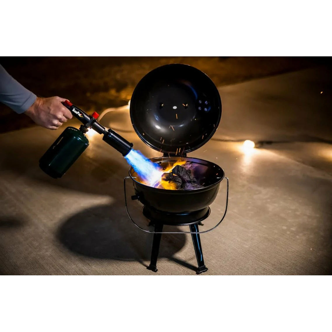 Person using a butane torch to light charcoal in a grill.