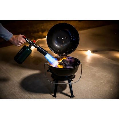 Person using a butane torch to light charcoal in a grill.