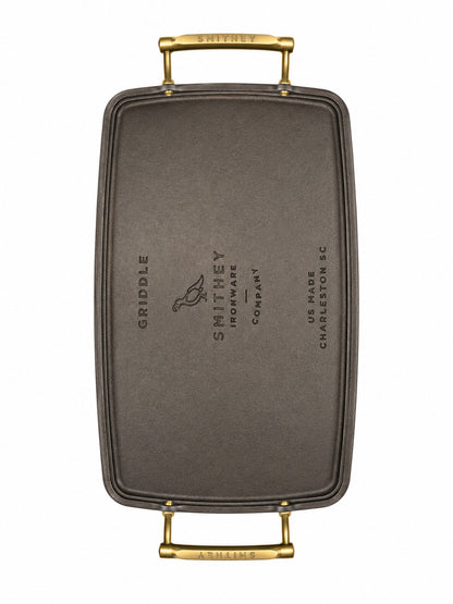 Smithey Ironware Double Burner Griddle bottom with gold handles on a white background