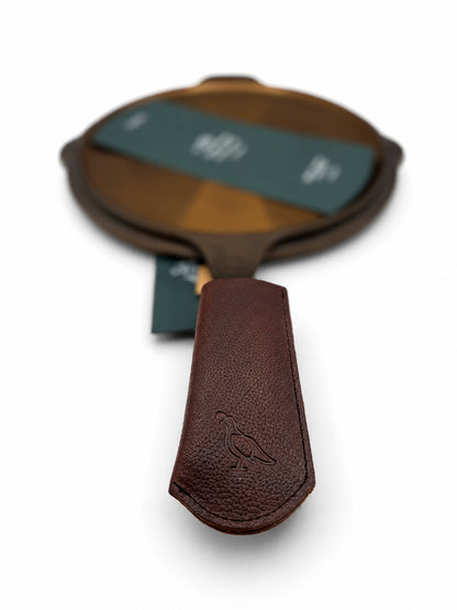 Smithey Ironware Brown Leather Skillet Sleeve on a skillet on a white background