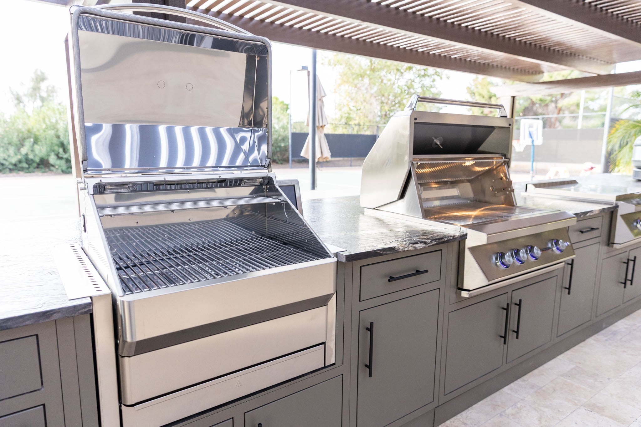 Full custom outdoor kitchen island with built-in grills, griddle and granite countertops under a pergola - Scottsdale, AZ